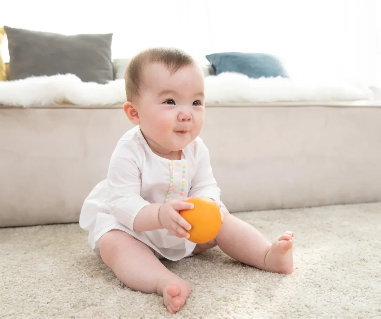 baby playing with ball on clean carpet